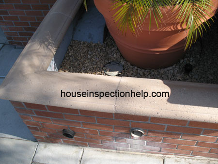 brick planter in front of building with two water drainage pipes